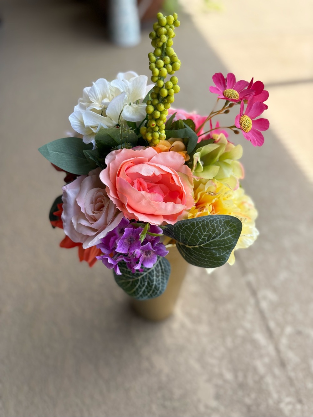 Floral arrangement features vibrant artificial flowers, including pink coral